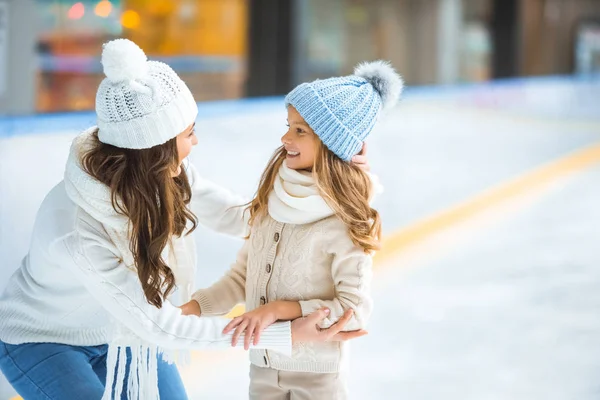 Side view of happy mother and daughter looking at each other on skating rink — Stock Photo