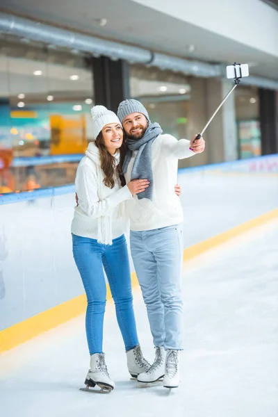 Cheerful couple taking selfie on smartphone together while spending time on skating rink — Stock Photo