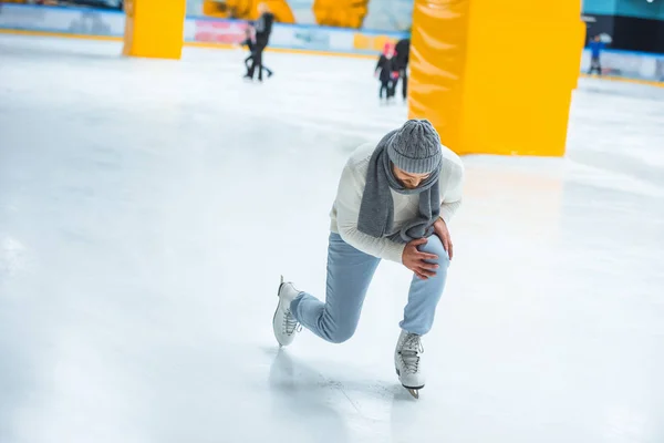 Homem ferido joelho enquanto patinava na pista de gelo — Fotografia de Stock