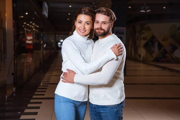 Sonriente pareja en suéteres blancos abrazando y mirando a la cámara - foto de stock