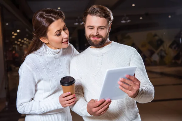 Portrait of couple in white knitted sweaters using digital tablet together — Stock Photo