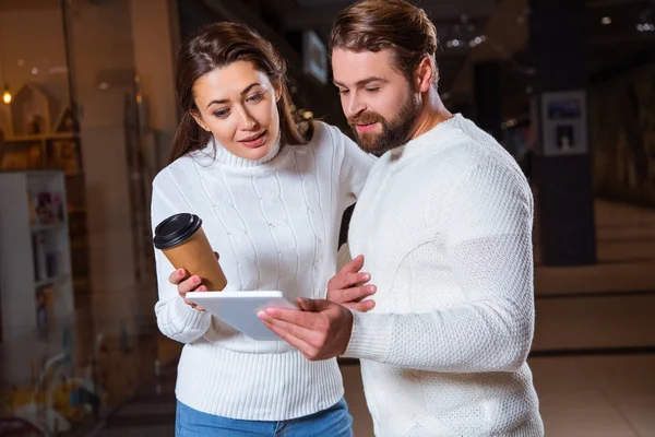 Pareja en suéteres de punto blanco usando tableta digital juntos - foto de stock