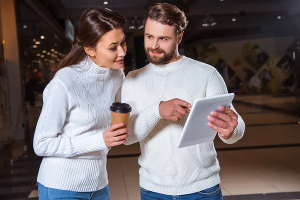 Portrait of couple in white knitted sweaters using digital tablet together — Stock Photo