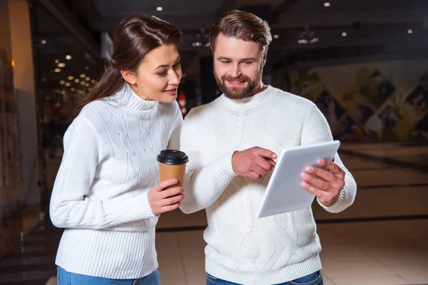 Porträt eines Paares in weißen Strickpullovern, das gemeinsam ein digitales Tablet benutzt — Stockfoto