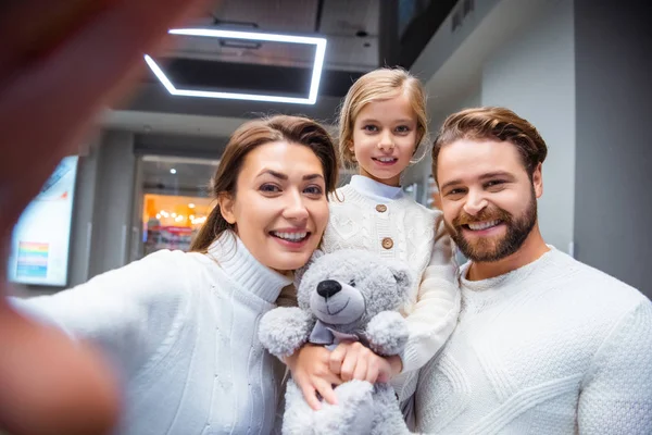 Camera point of view of cheerful family in white sweaters taking selfie together — Stock Photo