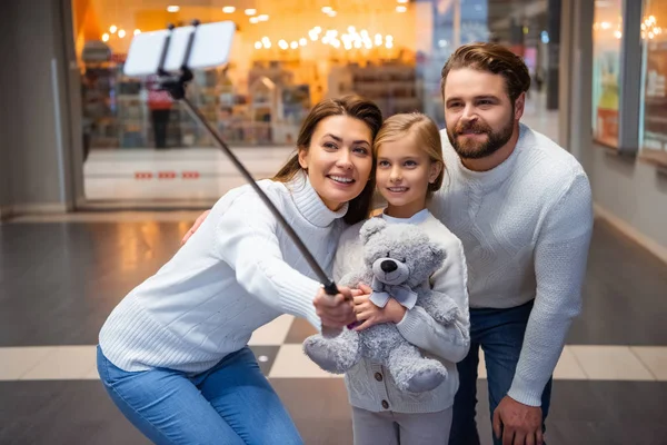 Усміхнена сім'я в білих светрах приймає селфі на смартфон разом — стокове фото