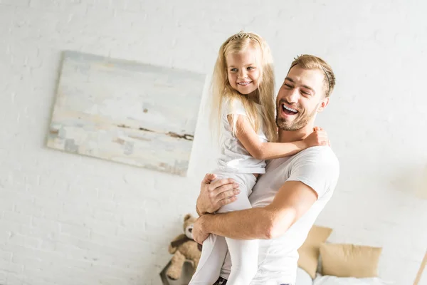 Feliz padre llevando adorable hijita en casa - foto de stock