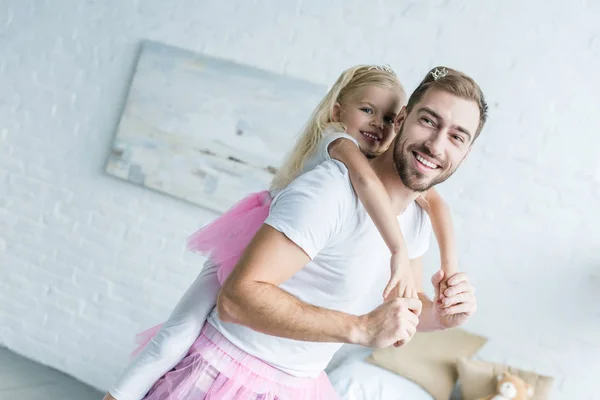 Adorable little daughter in pink tutu skirt hugging happy father at home — Stock Photo