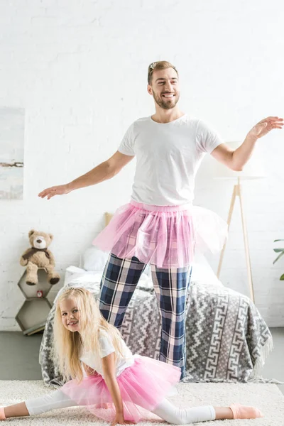 Happy father and daughter in pink tutu skirts having fun and dancing together at home — Stock Photo