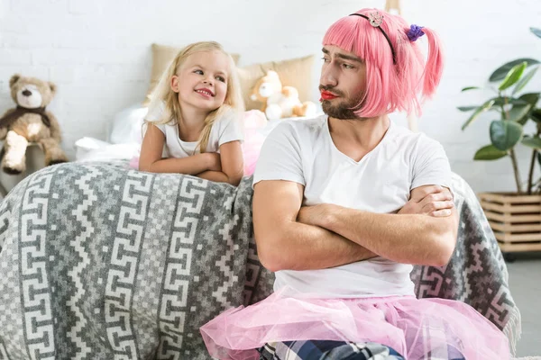 Adorable happy daughter looking at father in pink wig and tutu skirt — Stock Photo