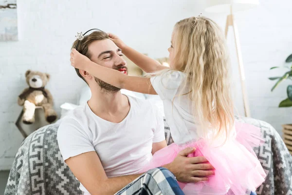 Cute little daughter in pink tutu skirt wearing headband with crown to happy father — Stock Photo