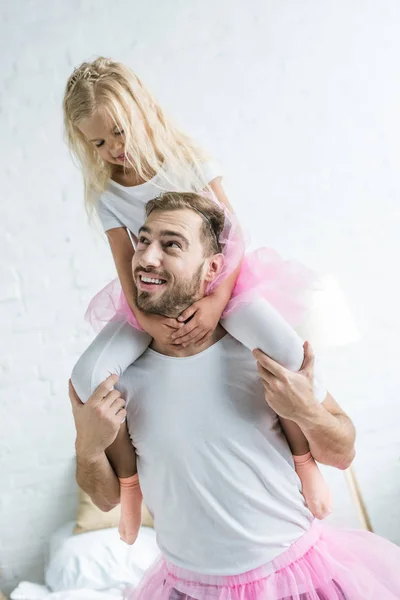 Happy father carrying adorable little daughter in pink tutu skirt on neck — Stock Photo