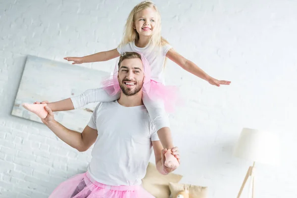 Pai feliz em saia tutu rosa carregando adorável sorrindo filha no pescoço — Fotografia de Stock