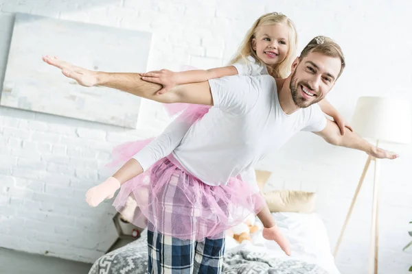 Heureux père et adorable petite fille en tutu rose jupes piggyback et sourire à la caméra — Photo de stock