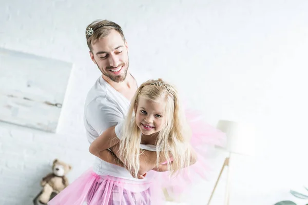Счастливый отец и очаровательная маленькая дочь в розовых юбочках пачки танцуют дома — стоковое фото