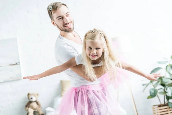 Счастливые отец и дочь в розовых юбочках пачки танцуют дома — стоковое фото