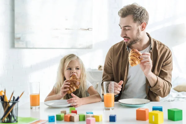 Vater und süße kleine Tochter essen zusammen Croissants — Stockfoto