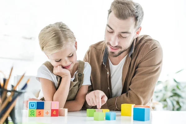 Glücklicher Vater und kleine Tochter lernen zu Hause Mathematik mit bunten Würfeln — Stockfoto