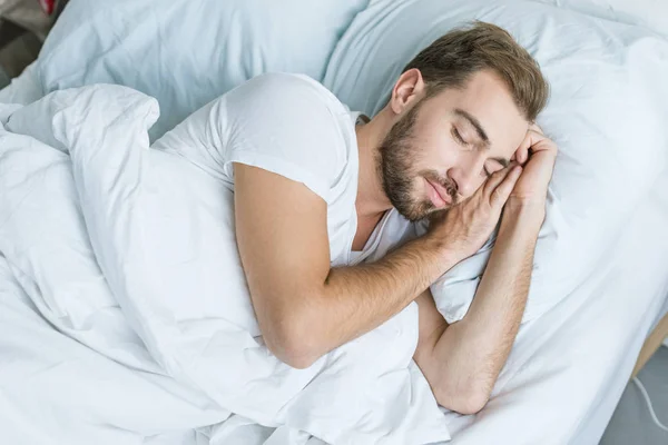 Vista ad alto angolo di bel giovane che dorme a letto — Foto stock