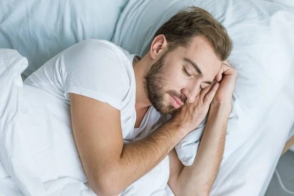 Vista ad alto angolo di bel giovane barbuto che dorme a letto — Foto stock