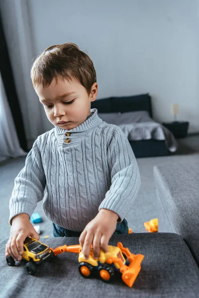 Enfoque selectivo de niño jugando con coches de juguete en la sala de estar en casa - foto de stock