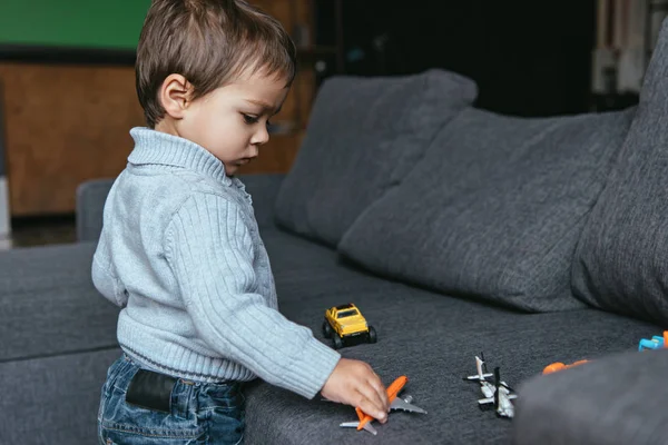 Sério menino brincando com avião de brinquedo na sala de estar em casa — Fotografia de Stock