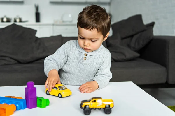 Selective focus of little kid playing with toy cars at table in living room at home — Stock Photo