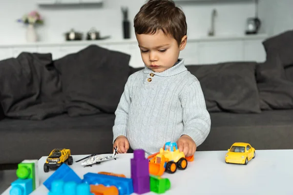 Junge spielt mit Spielzeugautos am Tisch im heimischen Wohnzimmer — Stockfoto