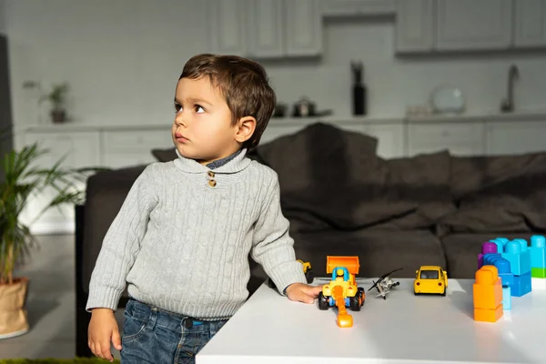 Niño jugando con coches de juguete en la mesa en la sala de estar en casa - foto de stock