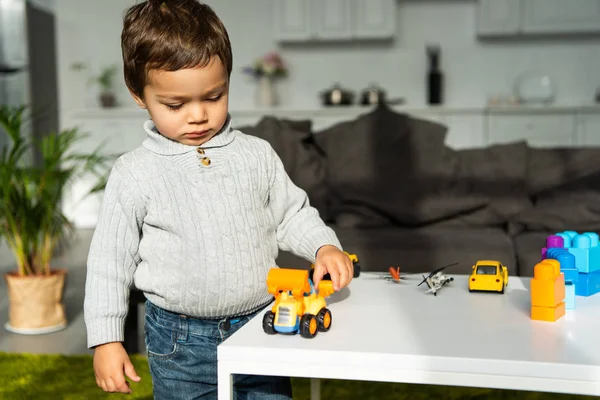 Child playing with toy cars at table in living room at home — Stock Photo