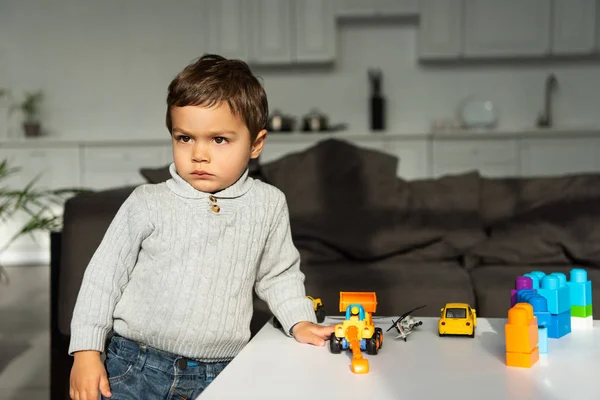 Серйозна гра з іграшковими машинами за столом у вітальні вдома — стокове фото