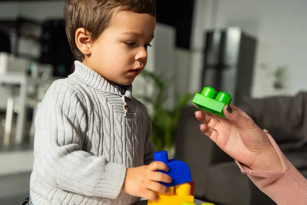 Vista parcial de la mujer jugando bloques de plástico con su hijo pequeño en casa - foto de stock