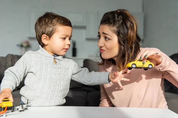 Piccolo figlio e sua madre giocare con auto giocattolo a casa — Foto stock