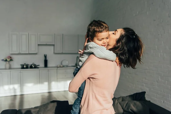 Женщина обнимает и держит очаровательного маленького сына на руках дома — стоковое фото