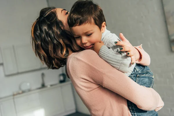 Vue rapprochée de la mère tenant adorable petit fils sur les mains à la maison — Photo de stock