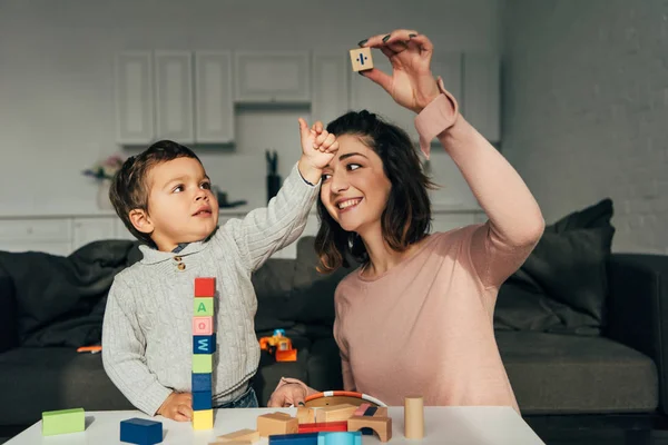 Bambino e sua madre giocando blocchi gioco torre di legno a casa — Foto stock