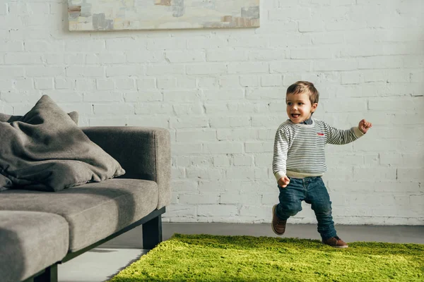 Glücklicher kleiner Junge läuft zu Hause im Wohnzimmer — Stockfoto