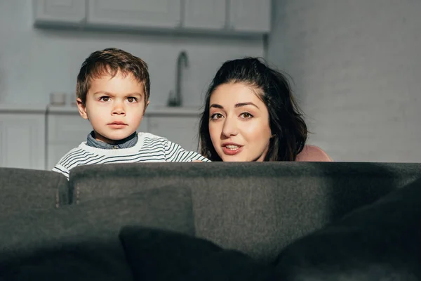 Retrato de la madre y el pequeño hijo sentado en el sofá en casa - foto de stock