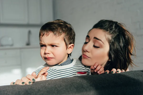 Vue rapprochée de la mère réconfortant petit fils pleurer sur le canapé à la maison — Photo de stock