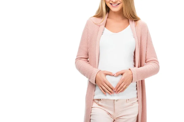 Vista recortada de la mujer embarazada que muestra el signo del corazón con las manos aisladas en blanco - foto de stock