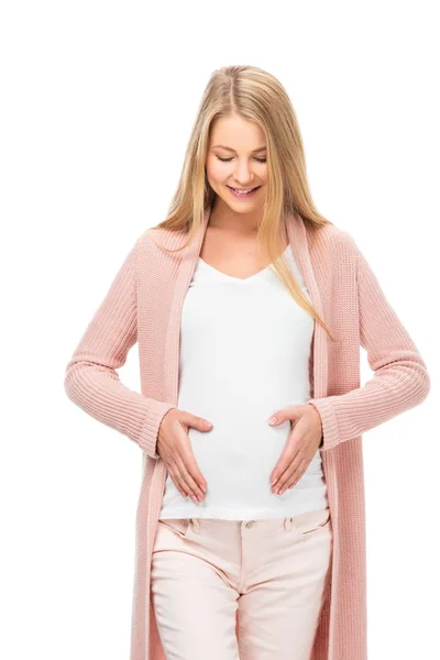 Sonriente embarazada rubia tocando vientre con ambas manos y mirando hacia abajo aislado en blanco - foto de stock