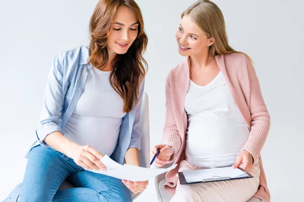 Mujeres embarazadas hablando en la clase prenatal aisladas en blanco - foto de stock