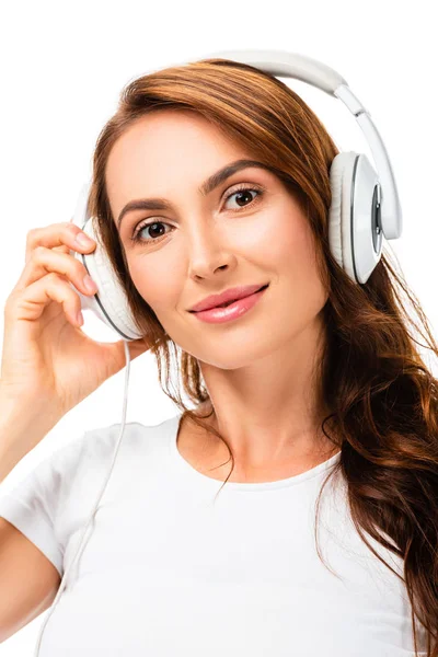 Close-up de mulher olhando para a câmera, ouvindo música e usando fones de ouvido isolados em branco — Fotografia de Stock