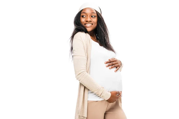 Belle femme enceinte afro-américaine tenant la main sur le ventre et regardant loin isolé sur blanc — Photo de stock