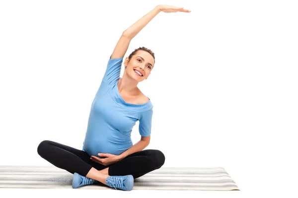 Incinta donna dai capelli castani stretching e sorridente isolato su bianco — Foto stock