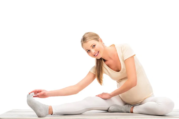 Pregnant blonde woman stretching and smiling isolated on white — Stock Photo