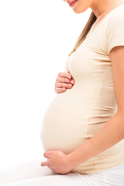 Vista recortada de la mujer embarazada manteniendo las manos en el vientre aislado en blanco - foto de stock