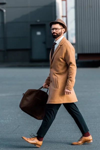 Hombre de negocios guapo con bolsa caminando en el techo - foto de stock