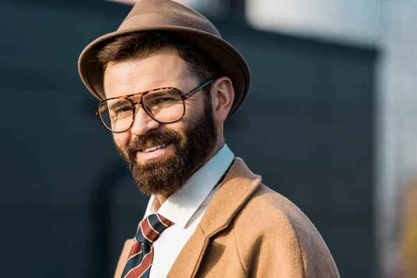 Close up of adult smiling businessman in glasses and hat looking at camera — Stock Photo