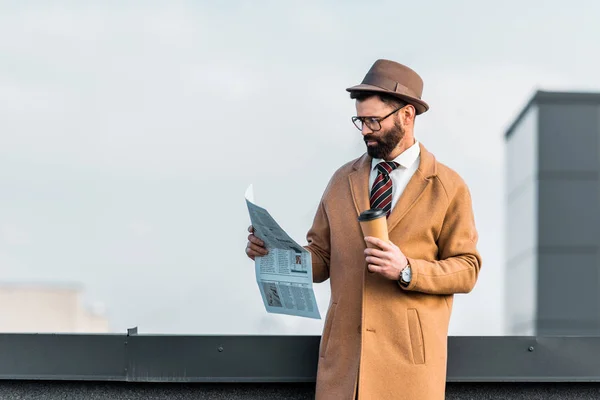 Gros plan d'un homme d'affaires lisant un journal et tenant une tasse jetable — Photo de stock